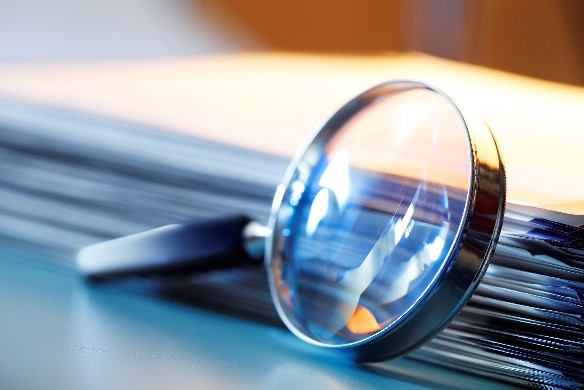 A magnifying glass resting against file folders.